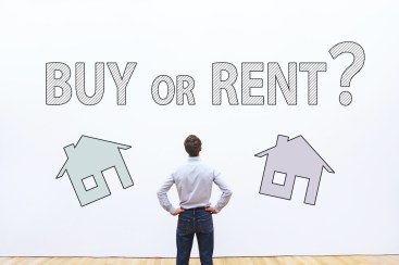 Man looks at sign to choose buy or rent.