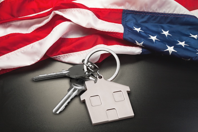 USA flag and key from home as symbol of VA loan on the desk.