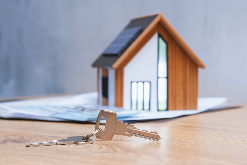 Miniature home with solar panels, keys and deeded dollars. Real estate deal concept, eco-friendly housing and green energy investment