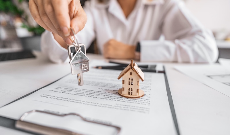Woman real estate agent gives keys paperwork and miniature house model. Concept of buying apartment, rental contract signing, trusted agency service and modern housing ownership
