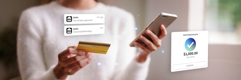 Woman performs international wire transfer via mobile banking app on a smartphone using her credit card for secure online payment