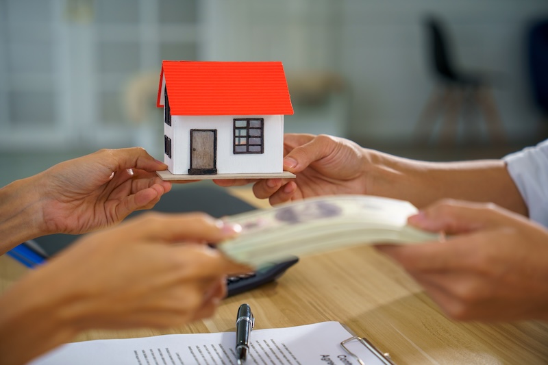 A real estate house purchase sale contract money payment mortgage loan agreement scene, hands exchange cash for model home, paperwork and pen on table in office, indoor, during closing deal
