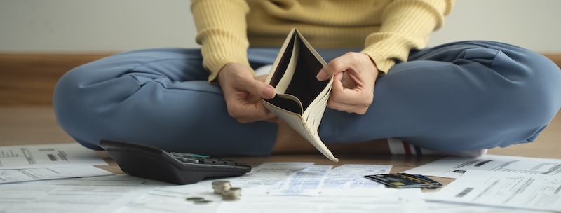 The stressed person sitting on the floor opening empty wallet